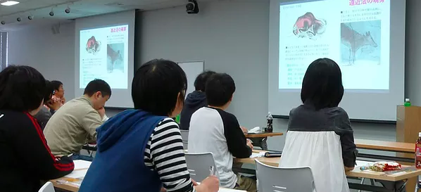 MANZEMIの案内に掲載された過去の対面講座で受講者が説明を聞く様子